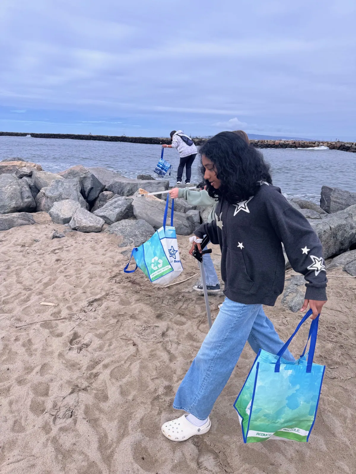 EcoQuest volunteer collecting litter along the shoreline at a Seal Beach cleanup